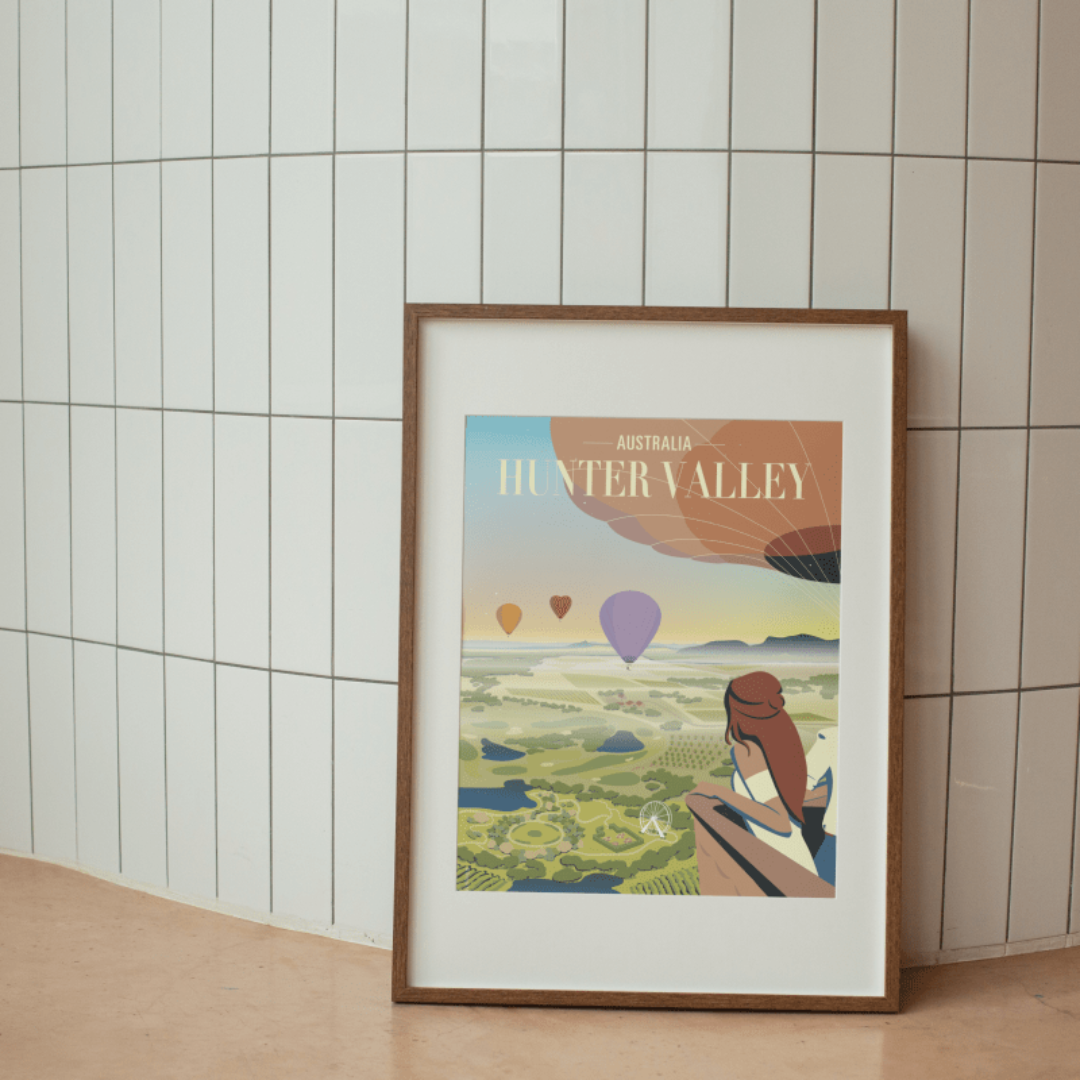 Framed Hunter Valley Balloon Sunrise Poster displayed against a modern tiled wall, showcasing an artistic view of hot air balloons floating over the scenic vineyards of Hunter Valley.