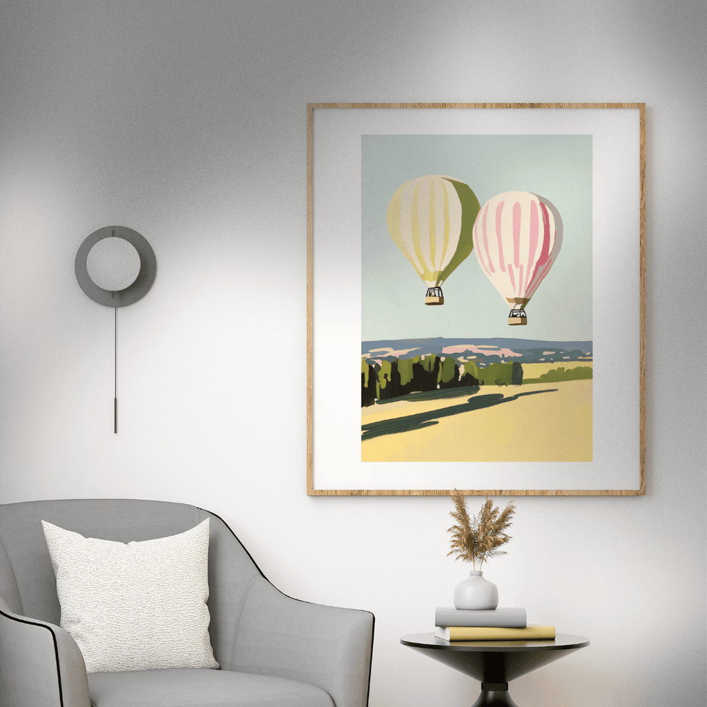 Framed artwork of hot air balloons on a wall above a gray armchair.