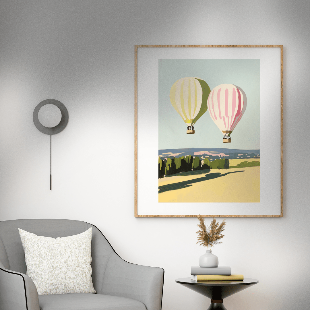 Framed artwork of hot air balloons on a wall above a gray armchair.