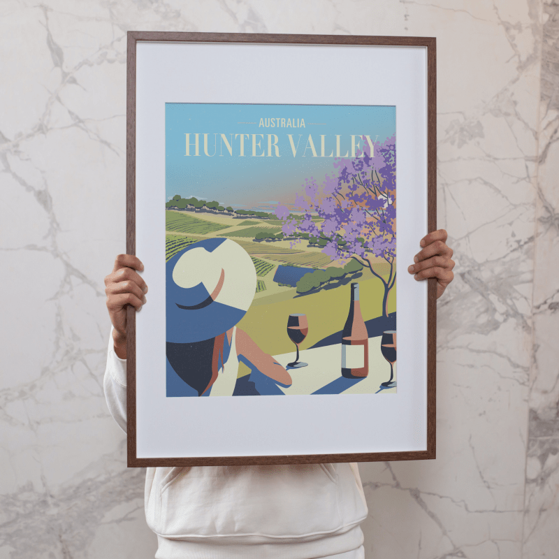 Person holding a framed Hunter Valley Bistro Sunset Poster, showcasing a stylish and scenic illustration of wine culture in Hunter Valley, perfect for home or office decor