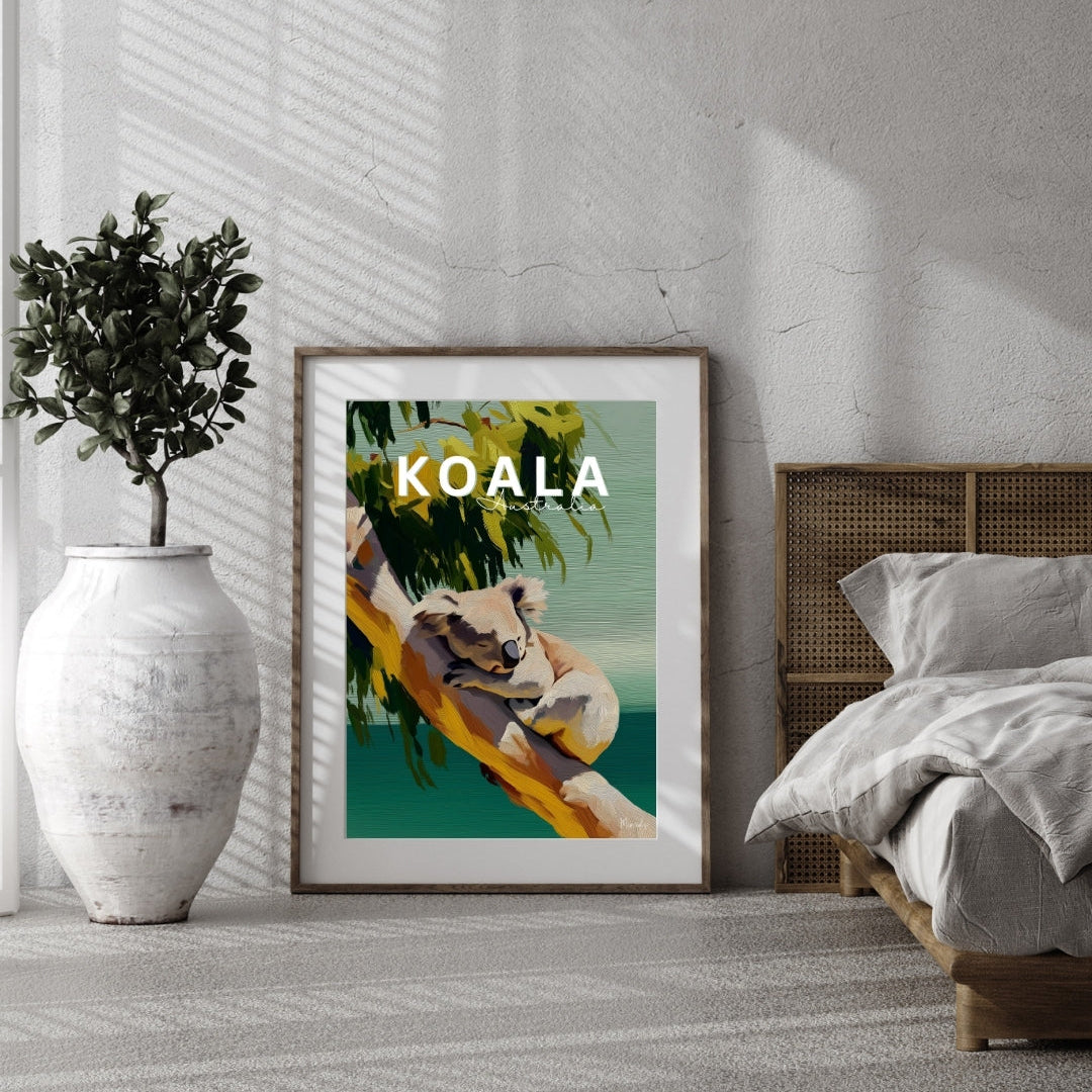 Framed artwork of a koala with the word 'KOALA' displayed in a room with a bed and plant.