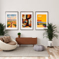 A set of three framed posters displayed in a stylish modern living room. The artworks include a kangaroo overlooking Hunter Valley vineyards, an abstract wine bottle design, and a vibrant vineyard scene with a red umbrella. 