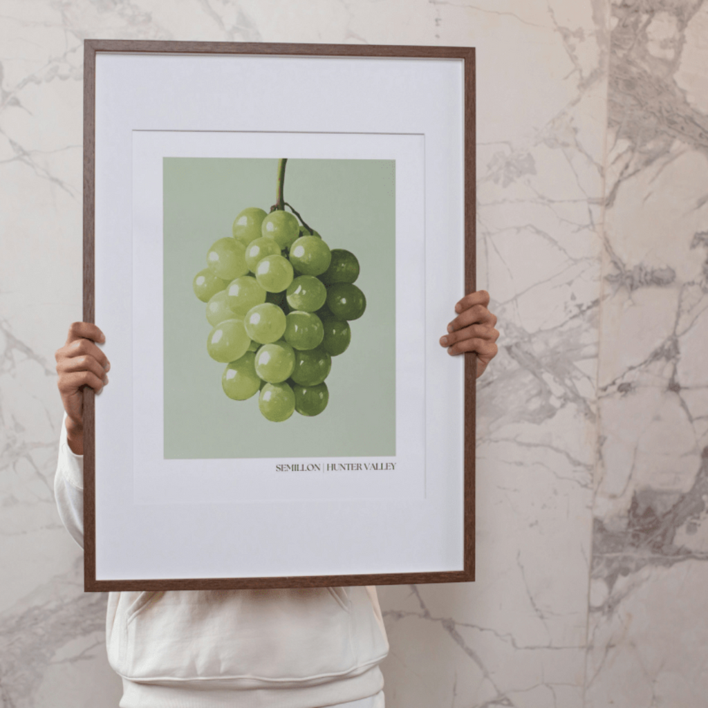 Person holding a framed Semillon grape poster in front of a marble wall. 
