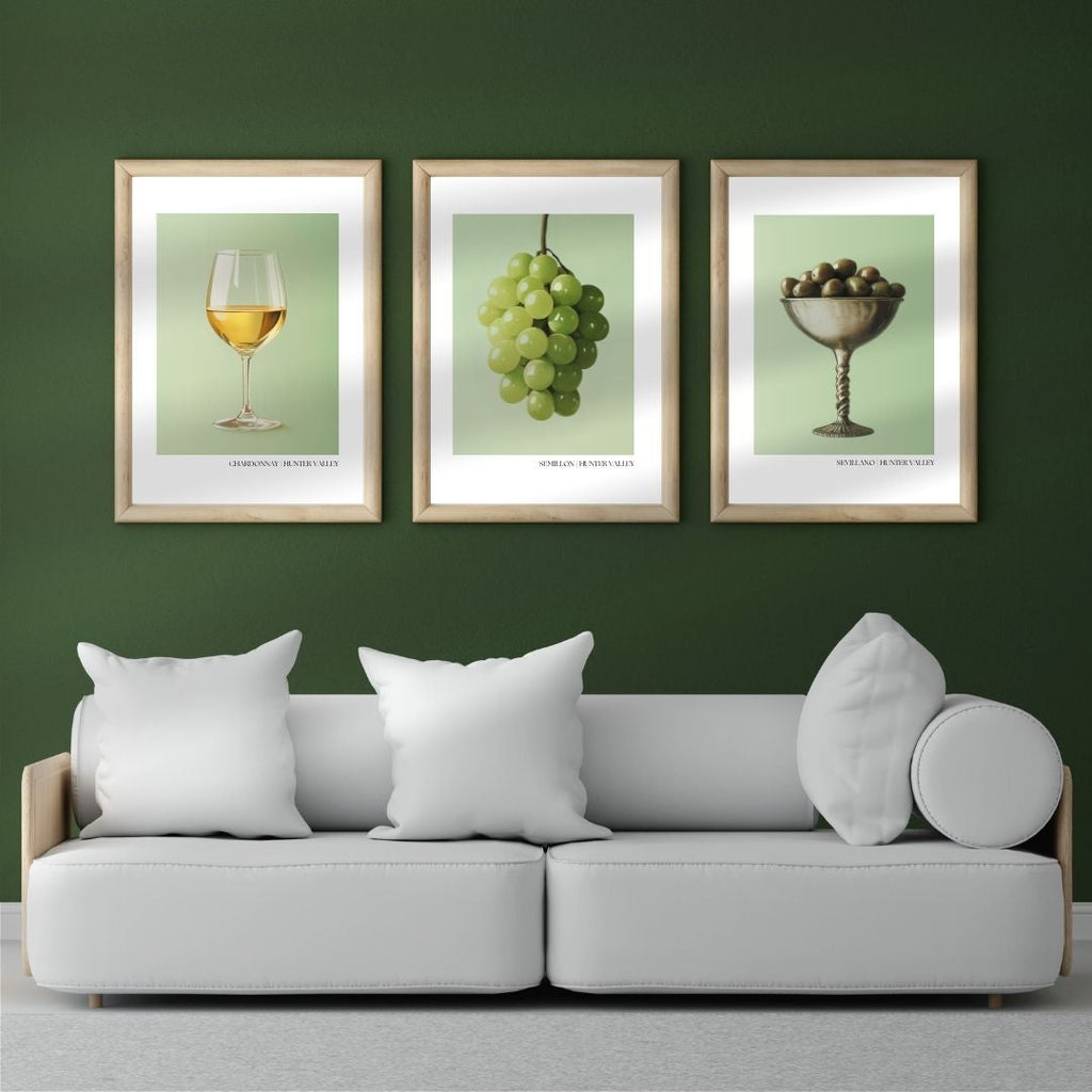 Gray sofa with white pillows against a green wall with framed pictures of wine, grapes, and fruit.