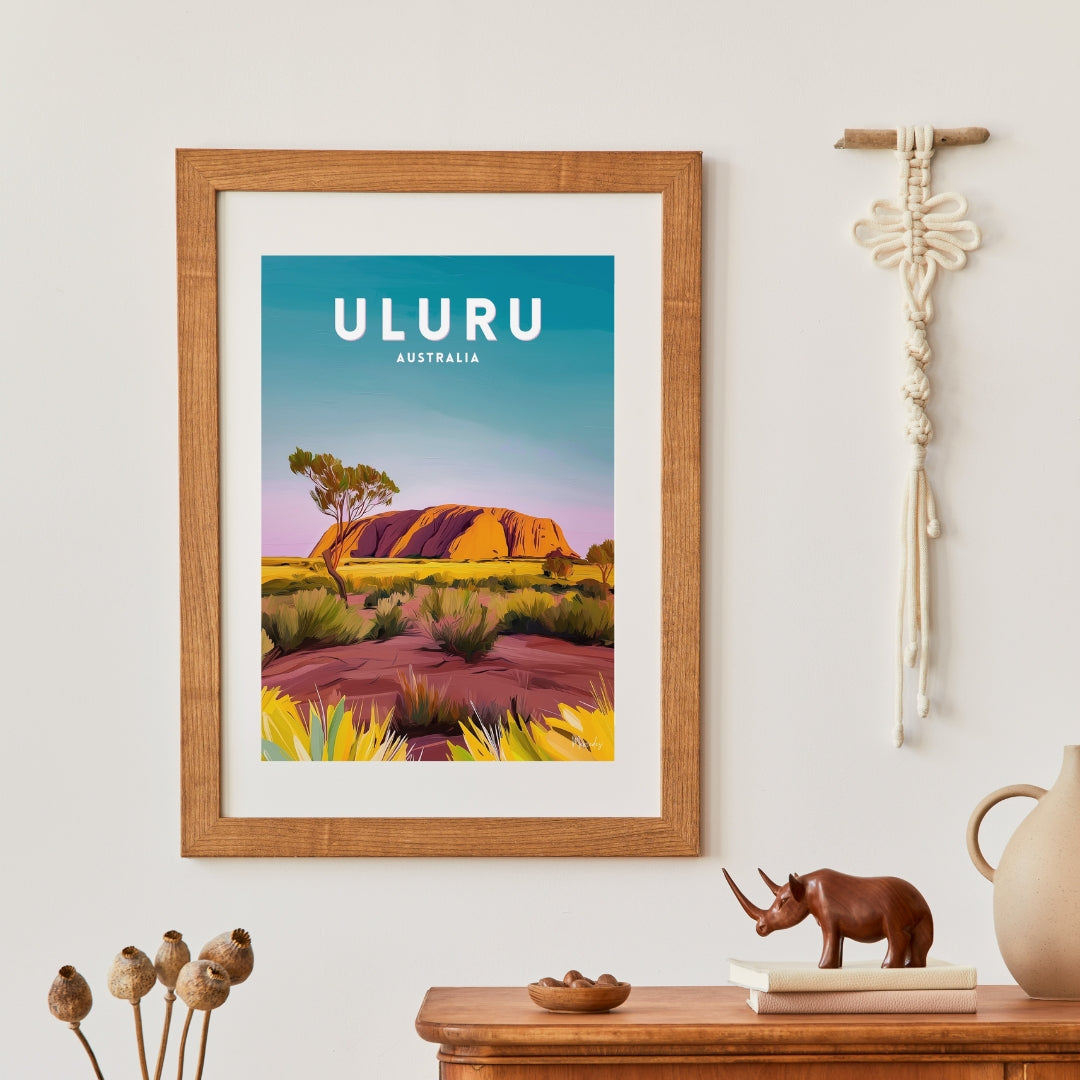 Framed poster of Uluru with a wooden cabinet and decorative items in the background